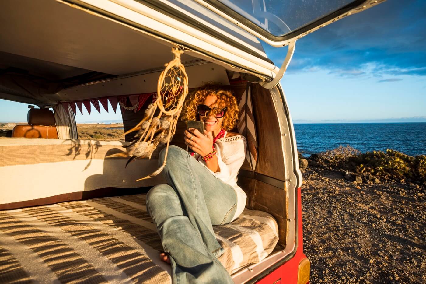 Femme heureuse et assise dans son vanlife.